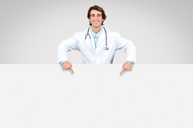 Hombre médico apuntando hacia abajo en el espacio de copia en un banner en blanco para texto o anuncio