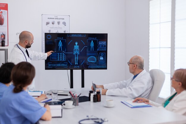 Hombre médico que presenta radiografía cerebral analizando la experiencia médica que trabaja en la sala de reuniones de conferencias