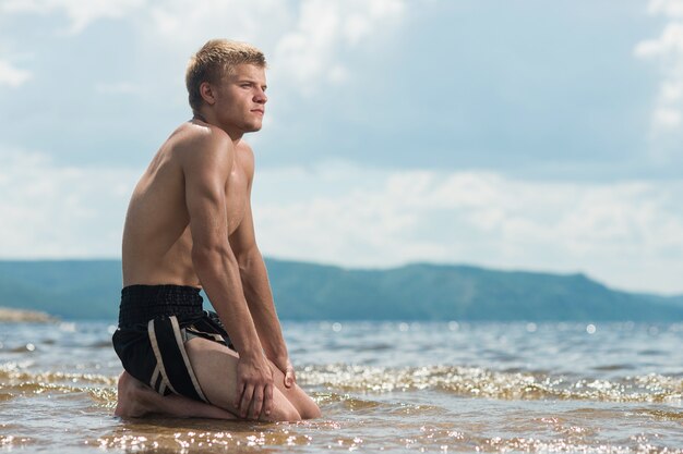 El hombre medita en la playa después de un entrenamiento.