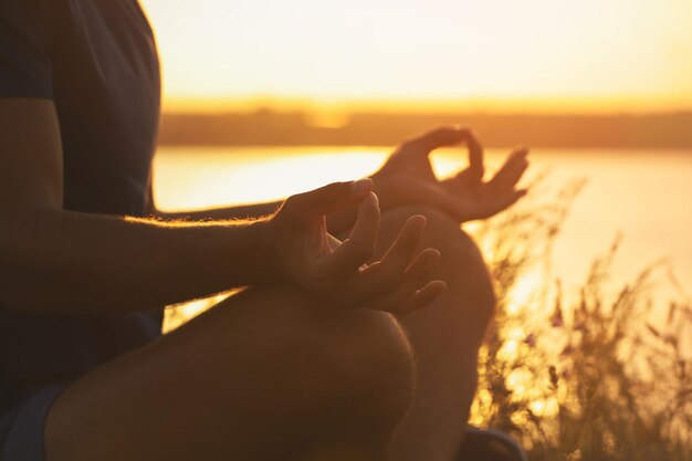 Hombre meditando cerca del río al atardecer closeup