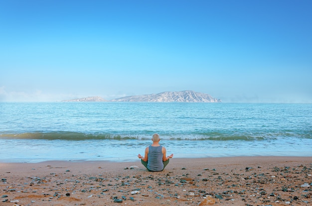 Hombre meditando en la orilla del mar