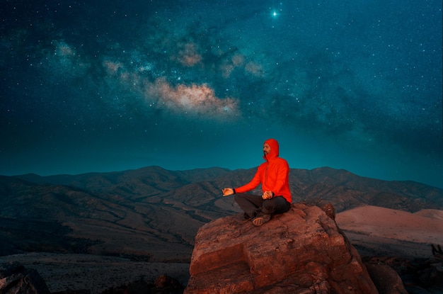 Hombre meditando solo en las colinas del desierto por la noche