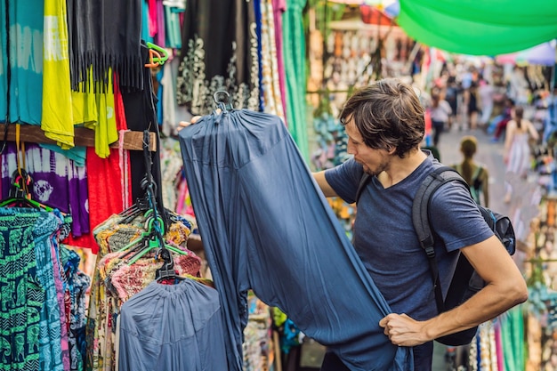 Hombre en un mercado en la tienda de recuerdos típica de ubud bali que vende recuerdos y artesanías de bali en el