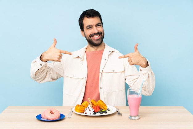 Hombre en una mesa desayunando gofres y un batido orgulloso y satisfecho