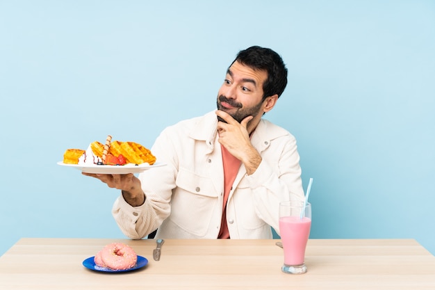 Hombre en una mesa desayunando gofres y un batido