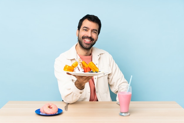 Hombre en una mesa desayunando gofres y un batido