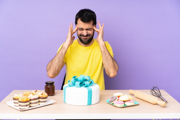 Foto hombre en una mesa con un gran pastel con dolor de cabeza