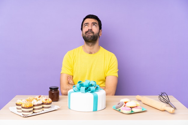 Hombre en una mesa con un gran pastel y mirando hacia arriba