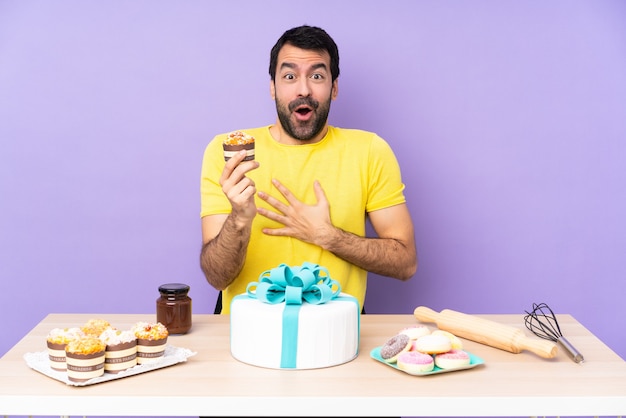 Hombre en una mesa con un gran pastel sobre fondo morado