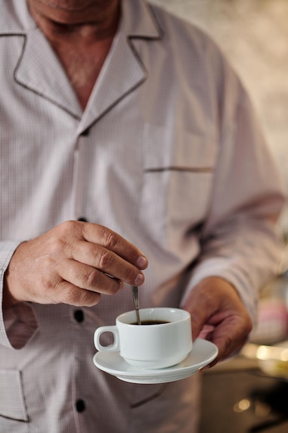 Hombre mezclando azúcar en taza