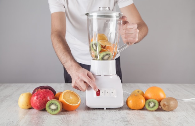 Hombre mezclando frutas con licuadora.