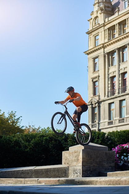 Hombre sin miedo mostrando truco en bicicleta en la ciudad