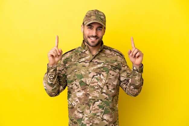 Hombre militar aislado sobre fondo amarillo apuntando hacia una gran idea