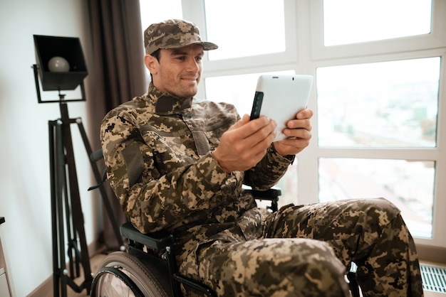 Hombre militar discapacitado usa tableta en silla de ruedas