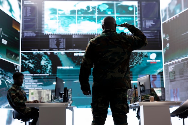Hombre militar mostrando el saludo honorario en el centro de mando de la base de operaciones