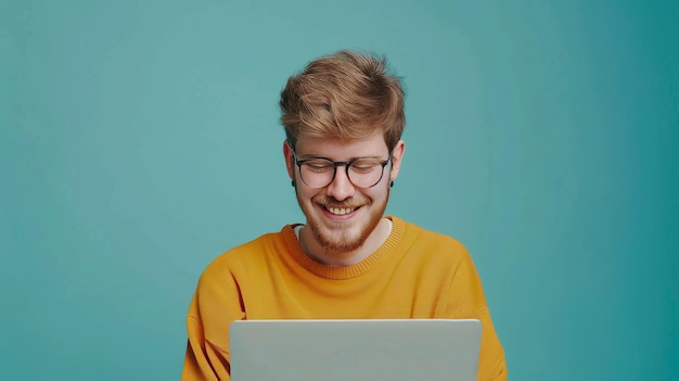 Hombre millennial feliz usando computadora portátil en fondo de estudio azul para hacer trabajo en línea o comunicarse