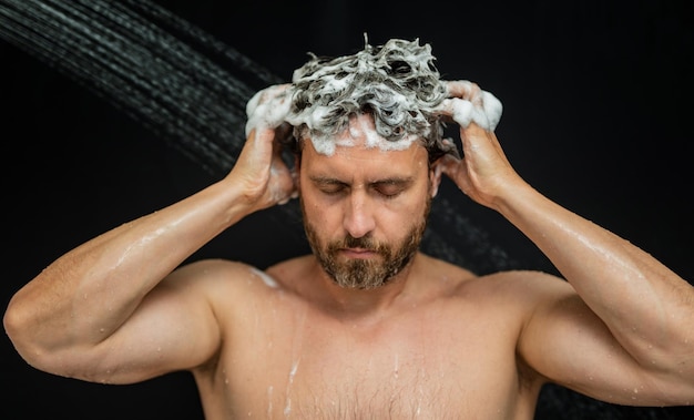 Hombre millennial lavando el cabello en el baño hombre bañándose cabeza de ducha en la bañera cara en espuma en la ducha