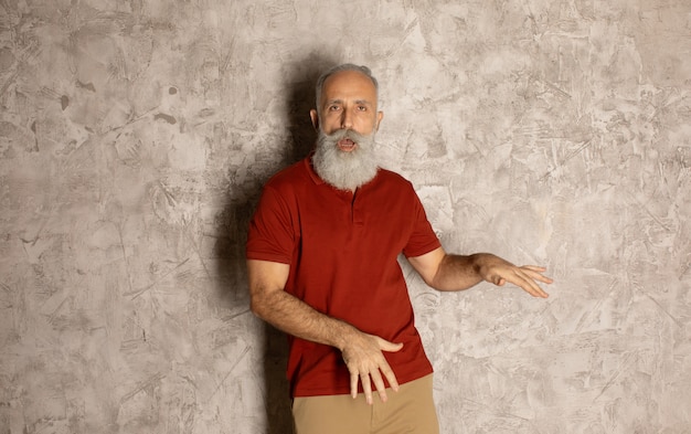 Hombre millonario senior feliz bailando sobre fondo gris.