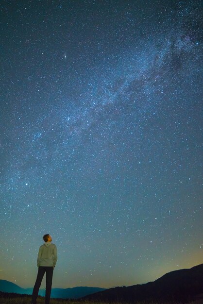 El hombre se para y mira al cielo con estrellas. Noche