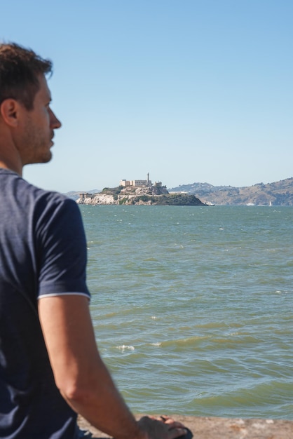 Foto hombre mira a alcatraz desde el paseo marítimo de san francisco