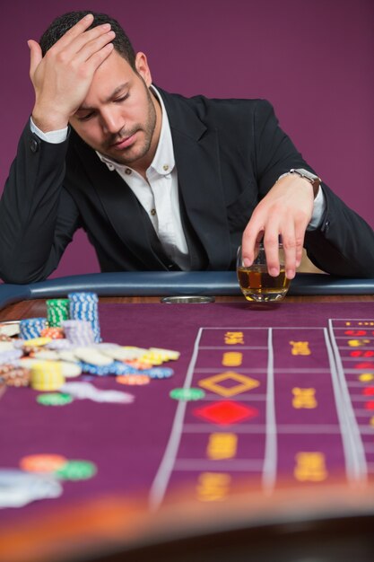 Foto hombre mirando abatido en la mesa de ruleta