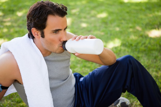 Hombre mirando hacia adelante mientras bebe de una botella de deportes