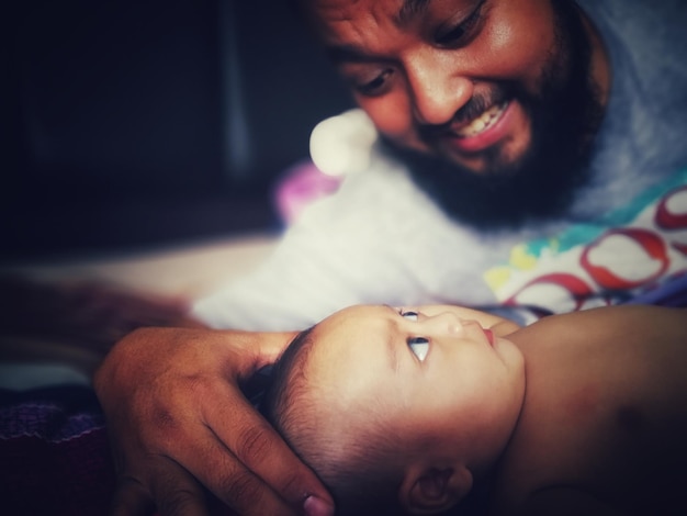 Foto hombre mirando al bebé en la cama