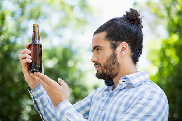 Hombre mirando la botella de cerveza en el parque