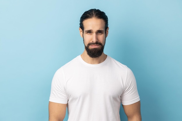 Foto hombre mirando a la cámara con cara de tristeza insatisfecha expresando dolor de mal humor