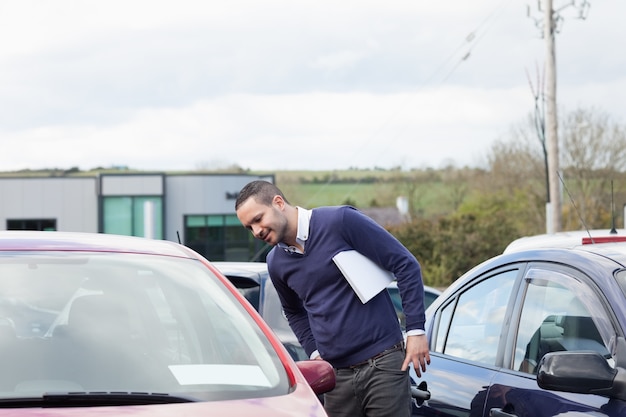 Foto hombre mirando un coche mientras se inclina