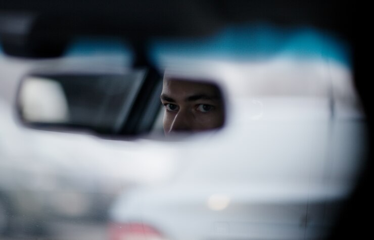 Hombre mirando en el espejo retrovisor mientras conduce
