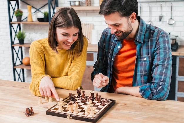 Foto hombre mirando a la esposa jugando el juego de ajedrez en el escritorio de madera