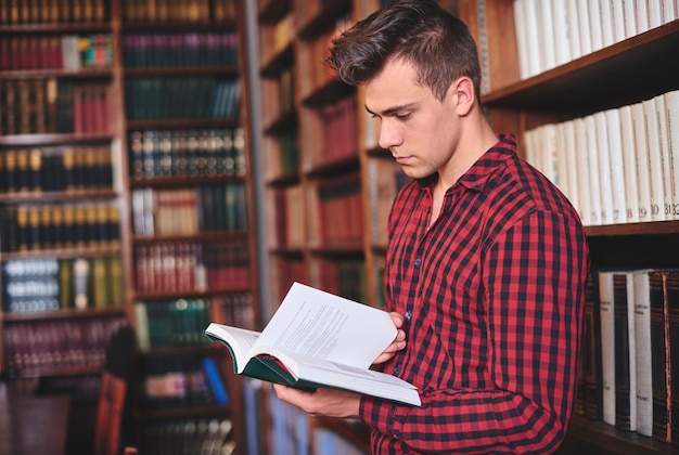 Hombre mirando un libro en la biblioteca