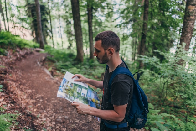 Hombre mirando el mapa mientras camina en el bosque