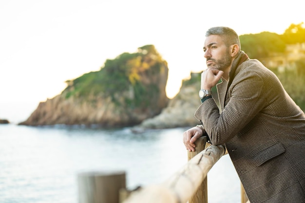 Hombre mirando el mar con montañas al fondo