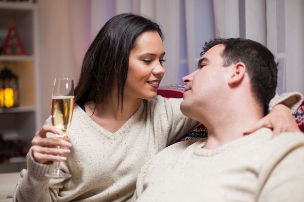 Hombre mirando a los ojos de su esposa sentado en el sofá celebrando la Navidad.