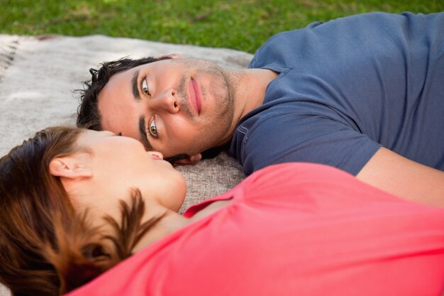 Hombre mirando a los ojos de sus amigos mientras está acostado en una colcha