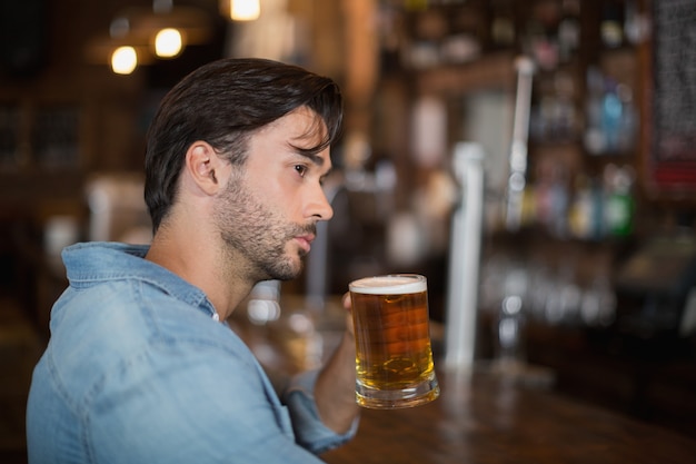 Hombre mirando a otro lado mientras bebe cerveza en el pub