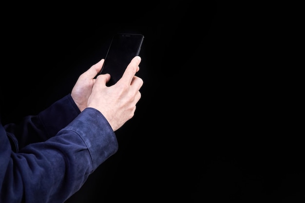 Hombre mirando la pantalla del teléfono inteligente en un fondo oscuro