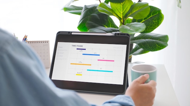 Hombre mirando planificador de marco de tiempo en la pantalla de la tableta digital