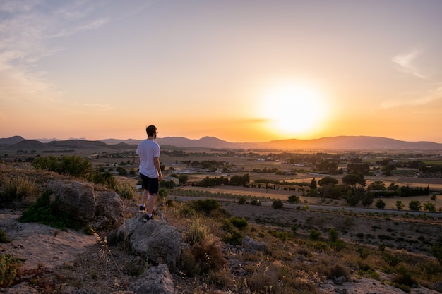 Hombre mirando la puesta de sol en una montaña