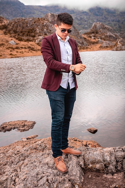 Foto hombre mirando el reloj en un paisaje de un lago.