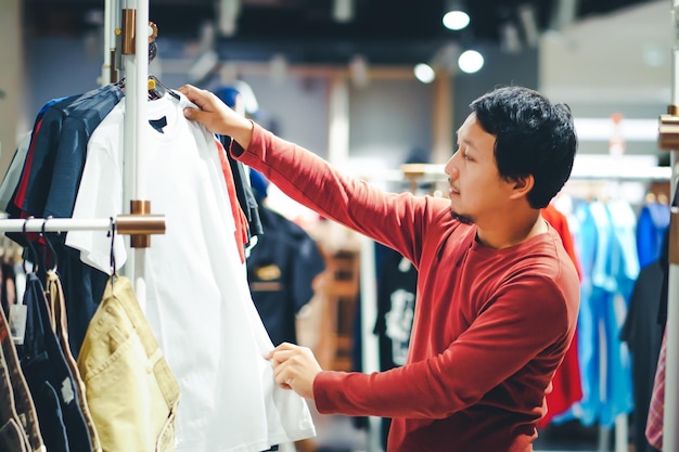 Hombre mirando ropa mientras está de pie en la tienda