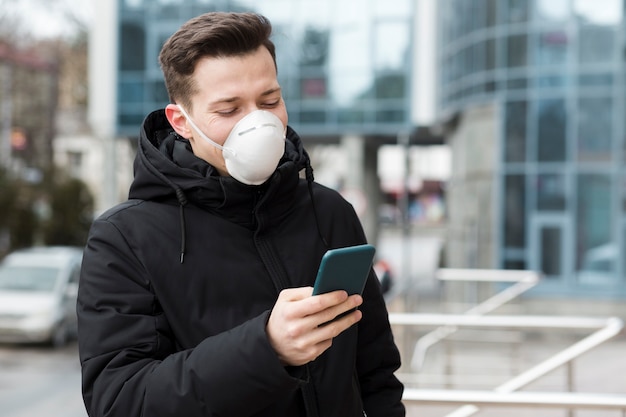 Hombre mirando su teléfono mientras usa una máscara médica