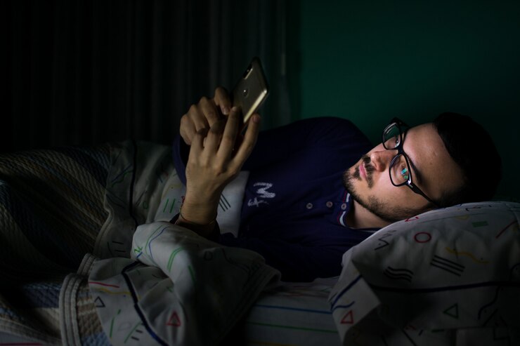 Hombre mirando su teléfono móvil en la cama por la noche