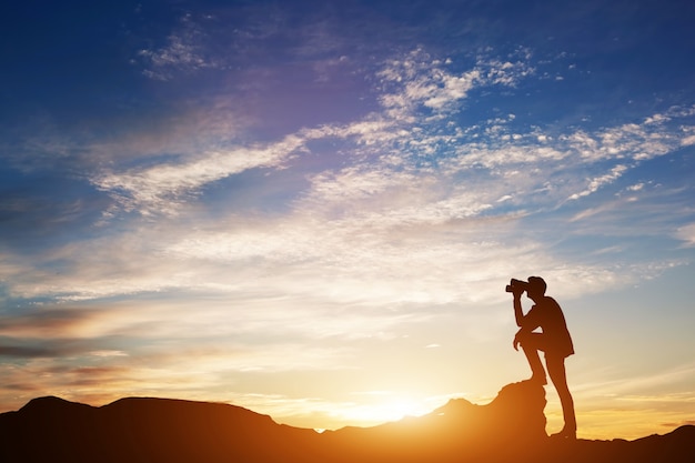 Foto hombre mirando a través de binoculares al atardecer.