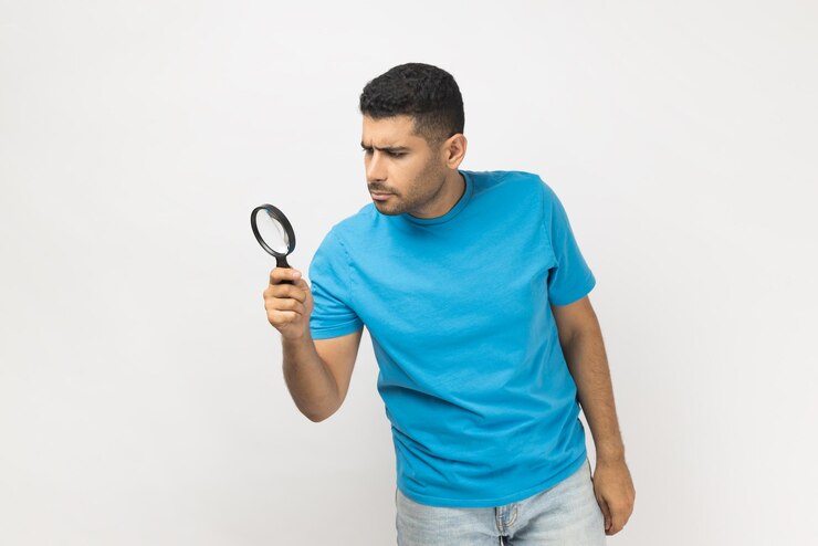 Foto hombre mirando a través de una lupa descubriendo algo explorando inspeccionando
