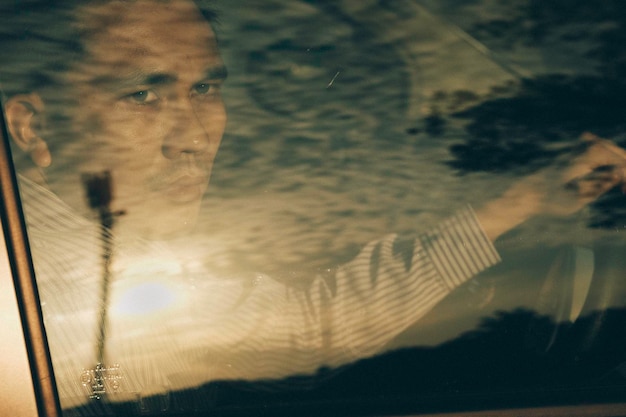 Foto hombre mirando por la ventana del coche durante la puesta de sol