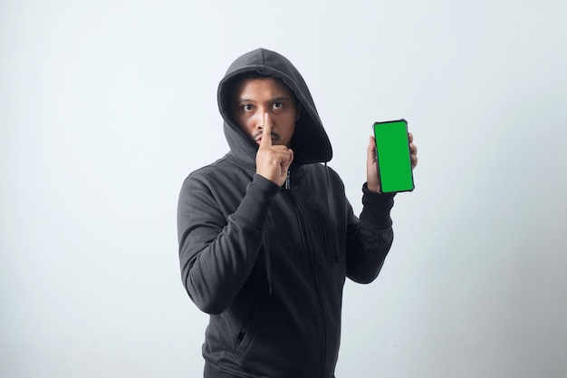 Foto hombre misterioso con capucha y sosteniendo el teléfono