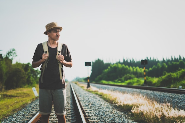 Hombre con mochila alejándose en el ferrocarril y enfatizar la paciencia y la encuesta tratando de avanzar hacia la meta.